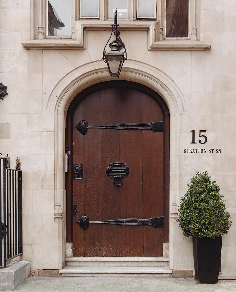 Arched wooden entrance door with a hanging lantern and potted tree